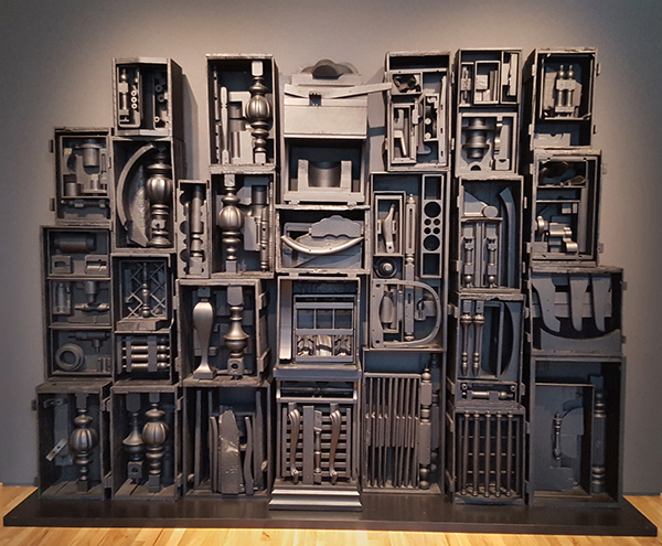 Industrial art installation: a wall of open crates filled with assorted metallic shapes and vintage hardware.