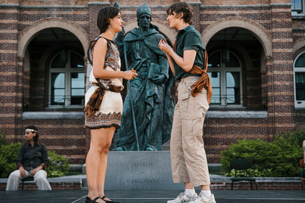 Rosalind and Orlando talking in front of a statue of St. Anselm